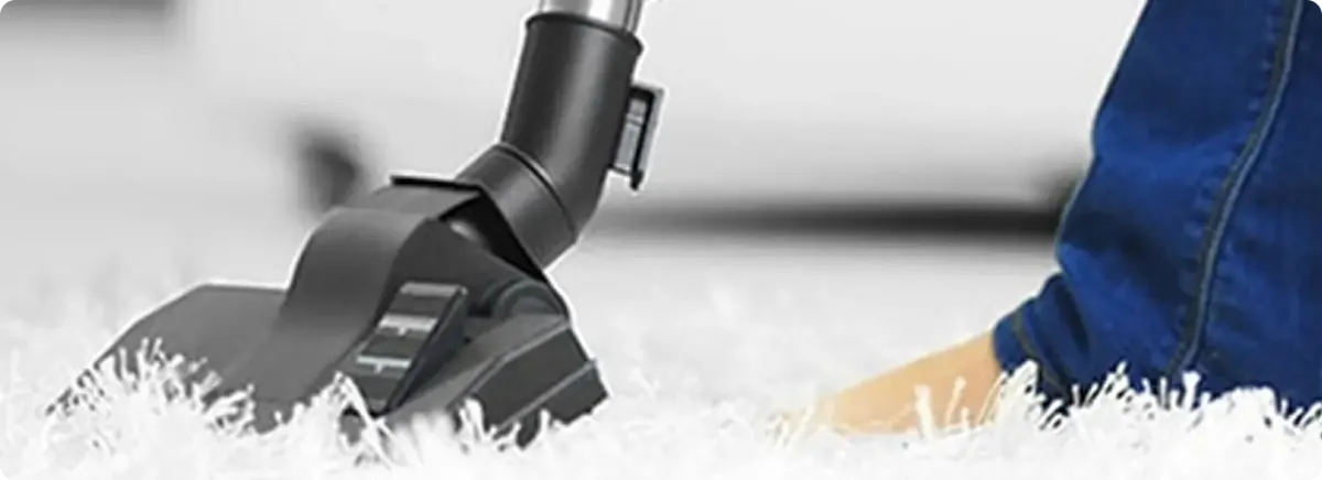Close-up of a professional vacuuming a white carpet in Satsuma.